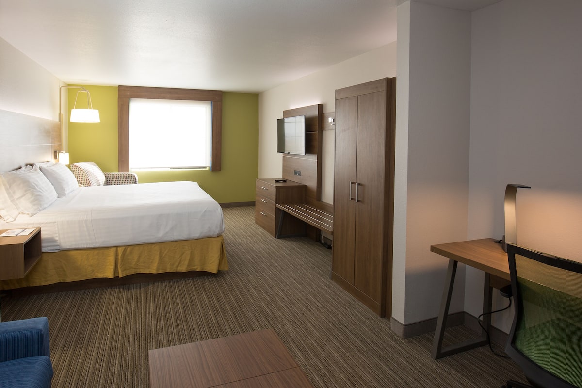 A hotel room with a bed, desk, TV, and wardrobe.