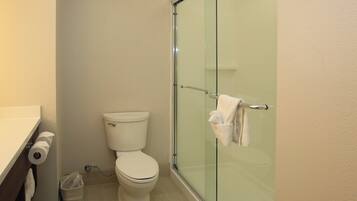 Un baño con inodoro, cabina de ducha de vidrio y un perchero para toallas.