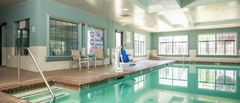 Una piscina interior con agua cristalina, una silla azul y una silla de salvavidas.