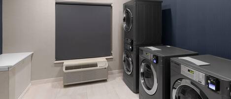 A laundry room with a wall-mounted dryer, a stacked washer and dryer unit, and a built-in air conditioning unit.