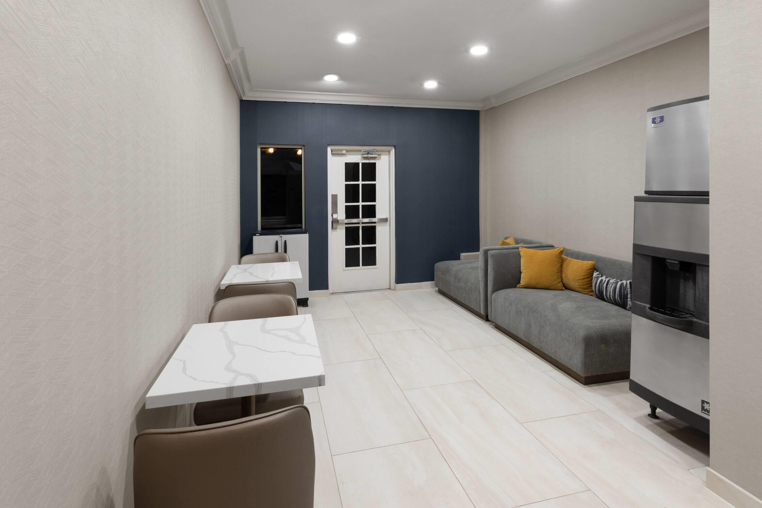 Un espacio habitable compacto con zona de comedor, sofá, refrigerador y una puerta con ventanal.