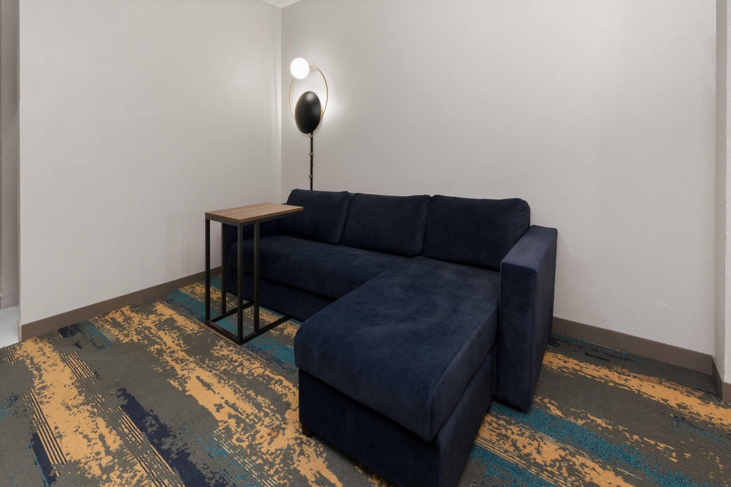A room with a dark blue sofa, a small table, and a floor lamp.
