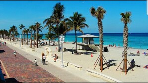 A beach with palm trees, a lifeguard tower, and people relaxing. - Hampton Inn by Hilton Hallandale Beach Aventura (Hallandale Beach)
