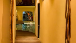 A wooden corridor leading to a pool area with a trash bin and a door at the end. - Kinbe Hotel Boutique (Playa del Carmen)