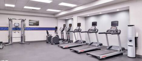 A gym with treadmills, ellipticals, and a weight machine.