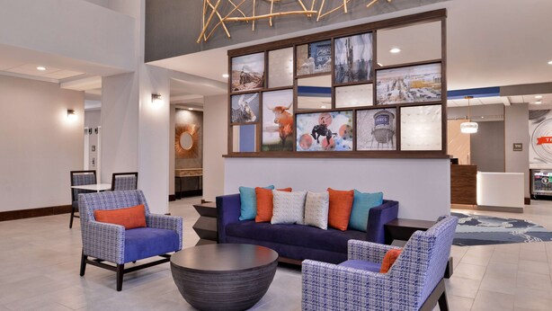 Eine Lobby mit einer Couch, Sesseln, einem Couchtisch und einer Wand mit gerahmten Bildern.