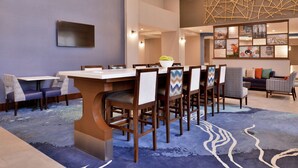 Ein Hotel-Speisesaal mit einem langen Tisch, mehreren Stühlen und einem gemusterten Teppich.