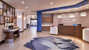 Eine Hotelhalle mit einer Rezeption, einer blauen Akzentwand und einem Willkommensschild.