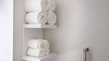 Une salle de bain avec des porte-serviettes blancs sur lesquels sont soigneusement pliées des serviettes.