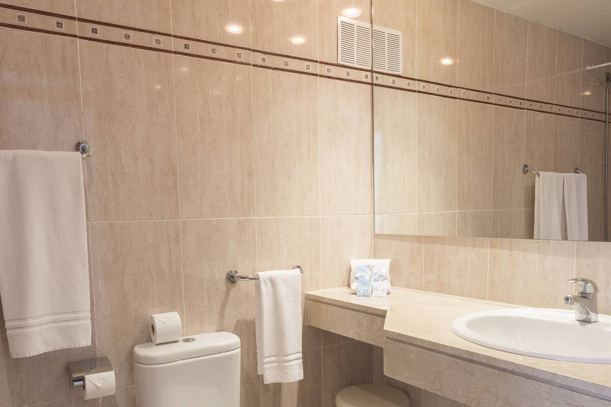 Ein modernes Badezimmer mit Toilette, Waschbecken und Spiegel.