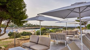 Outdoor seating with umbrellas, a view of the beach, and a pool area. - Hotel Globales Cala´n Bosch (Ciutadella de Menorca)
