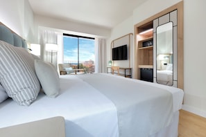 Een hotelkamer met een groot bed, een televisie, een bureau en een balkon met uitzicht.