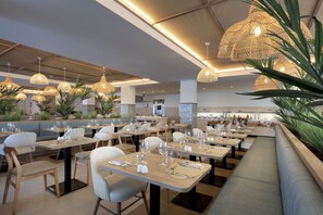 Un restaurante con varias mesas, sillas y lámparas de ratán colgantes.