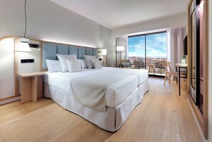 Een moderne hotelkamer met een groot bed, nachtkastjes, een bureau en een balkon met uitzicht.
