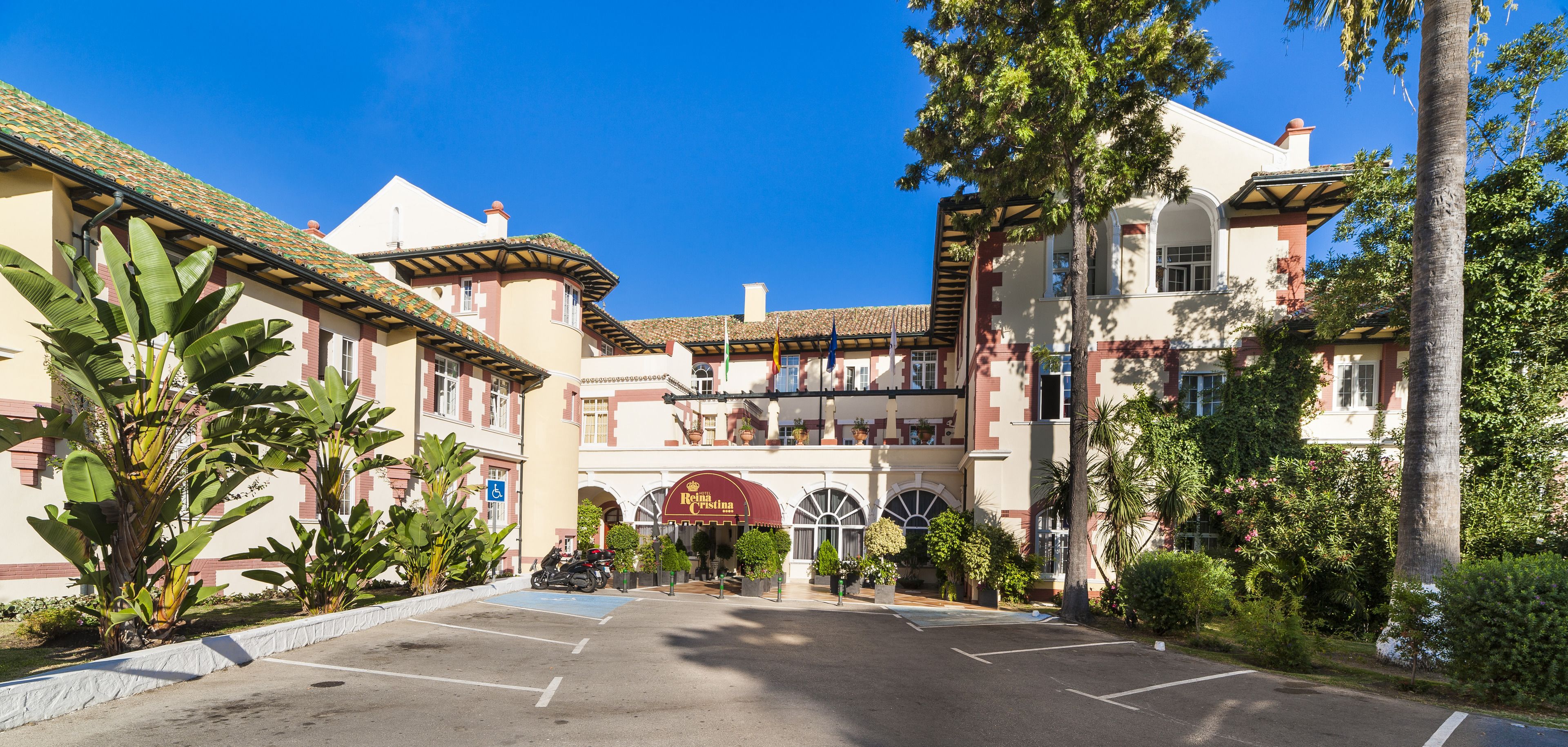 Un hotel con un patio central, un toldo rojo y un área de estacionamiento.