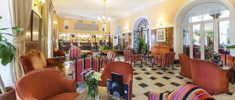 A spacious lobby with striped armchairs, a bar area, and a checkered floor.