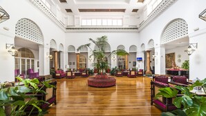 A spacious lobby with high ceilings, arched doorways, and a central seating area with a red circular rug.