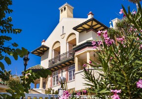 A multi-story building with balconies, large windows, and a clear blue sky.