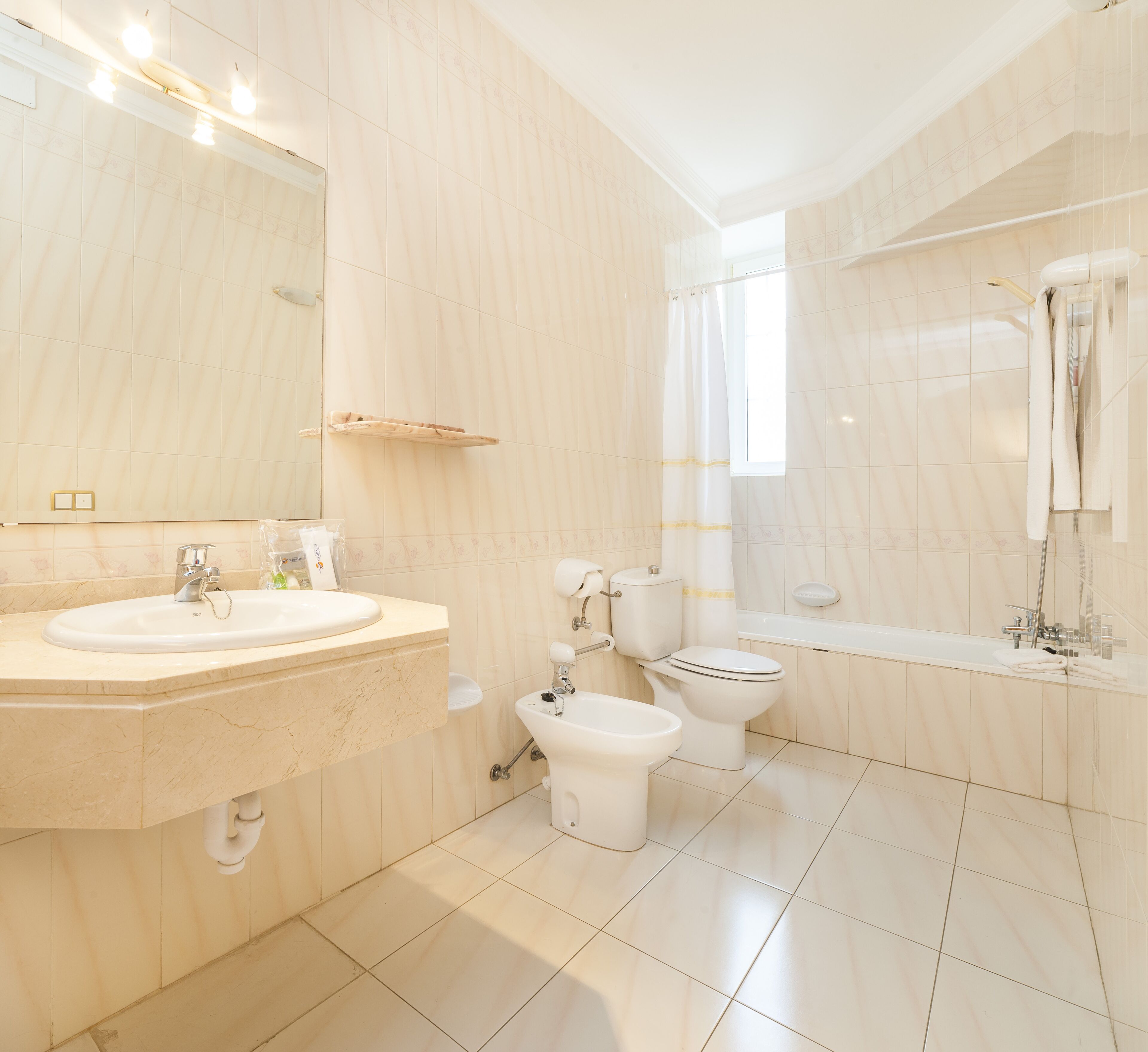 A modern bathroom with a sink, toilet, bidet, and bathtub.