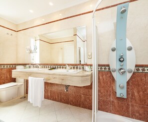 Une salle de bain avec un double lavabo, des toilettes, une douche et un miroir.