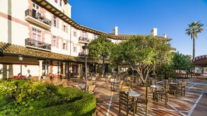 A courtyard with outdoor seating, a palm tree, and a building with balconies.