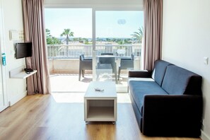 A modern living room with a sofa, a coffee table, and a TV on a wall. - Hotel Globales Los Delfines (Ciutadella de Menorca)