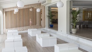 A modern interior with white seating areas, wooden slats, and potted plants. - Hotel Globales Los Delfines (Ciutadella de Menorca)