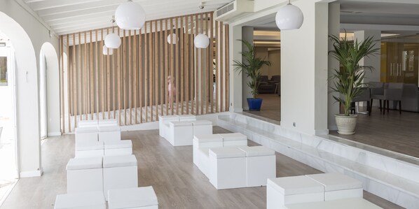 Ein modernes Interieur mit weißen Sitzbereichen, Holzlamellen und topfpflanzen.
