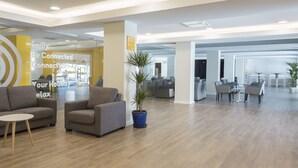 A modern office space with sofas, a small table, and a potted plant. - Hotel Globales Los Delfines (Ciutadella de Menorca)