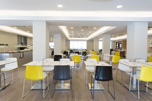 Une cafétéria spacieuse, dotée de tables et de chaises hautes, d’un éclairage abondant et d’un aménagement propre et moderne.
