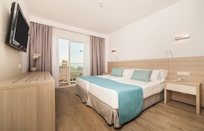 A hotel room with a bed, bedside table, TV, and a view of the outside. - Globales Mimosa (Calvia)