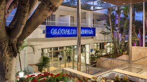 Un hotel con fachada de vidrio, zona de estar al aire libre y un cartel que dice "GLOBALES MEXICO".