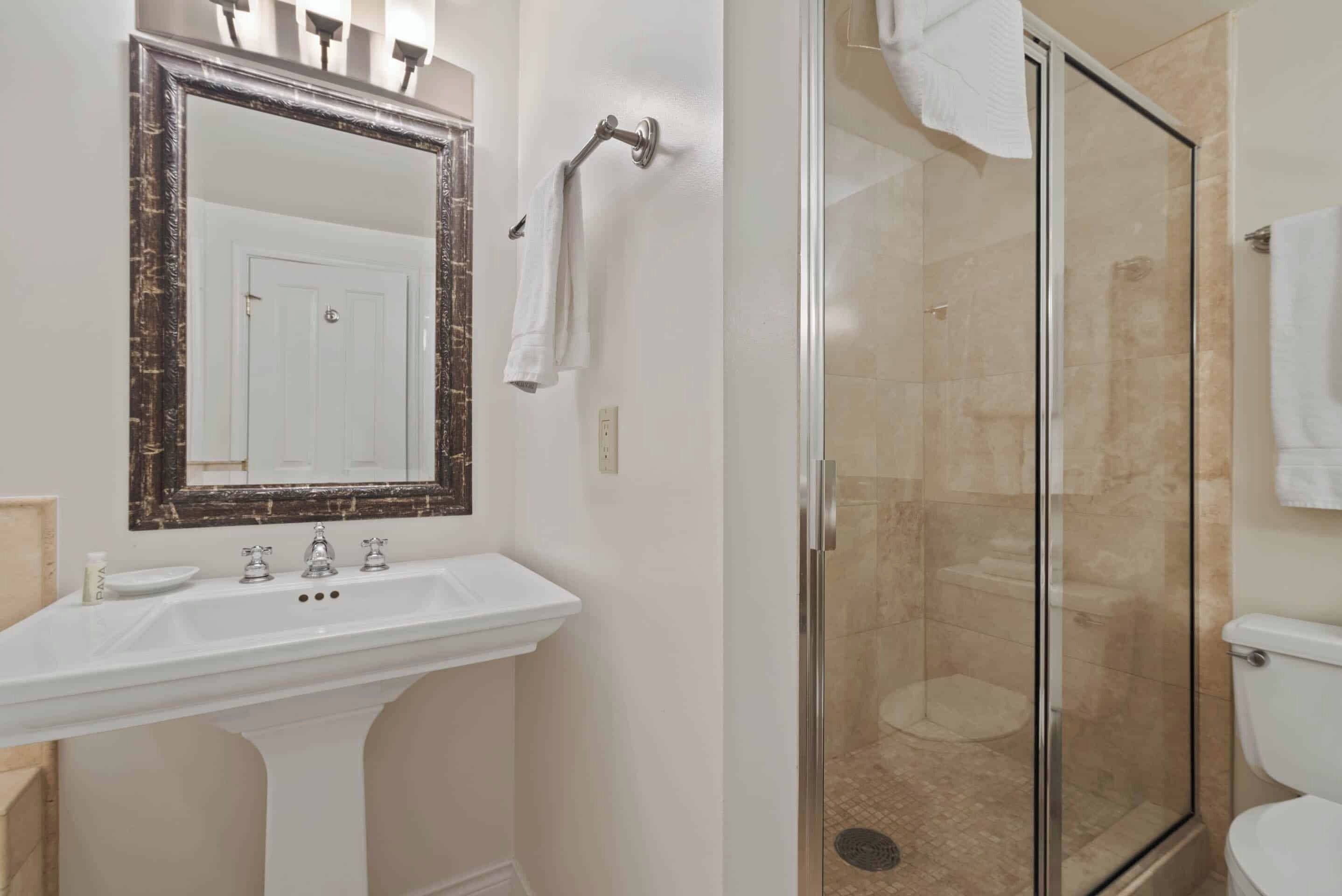 A bathroom with a white sink, a large mirror, and a glass-enclosed shower.