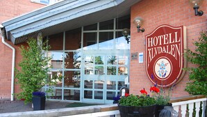 A hotel entrance with a sign reading "HOTELL ALVDALEN" and a view of the interior through the glass doors.