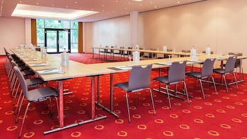 Un salón de conferencias con una larga mesa, sillas y botellas de agua.