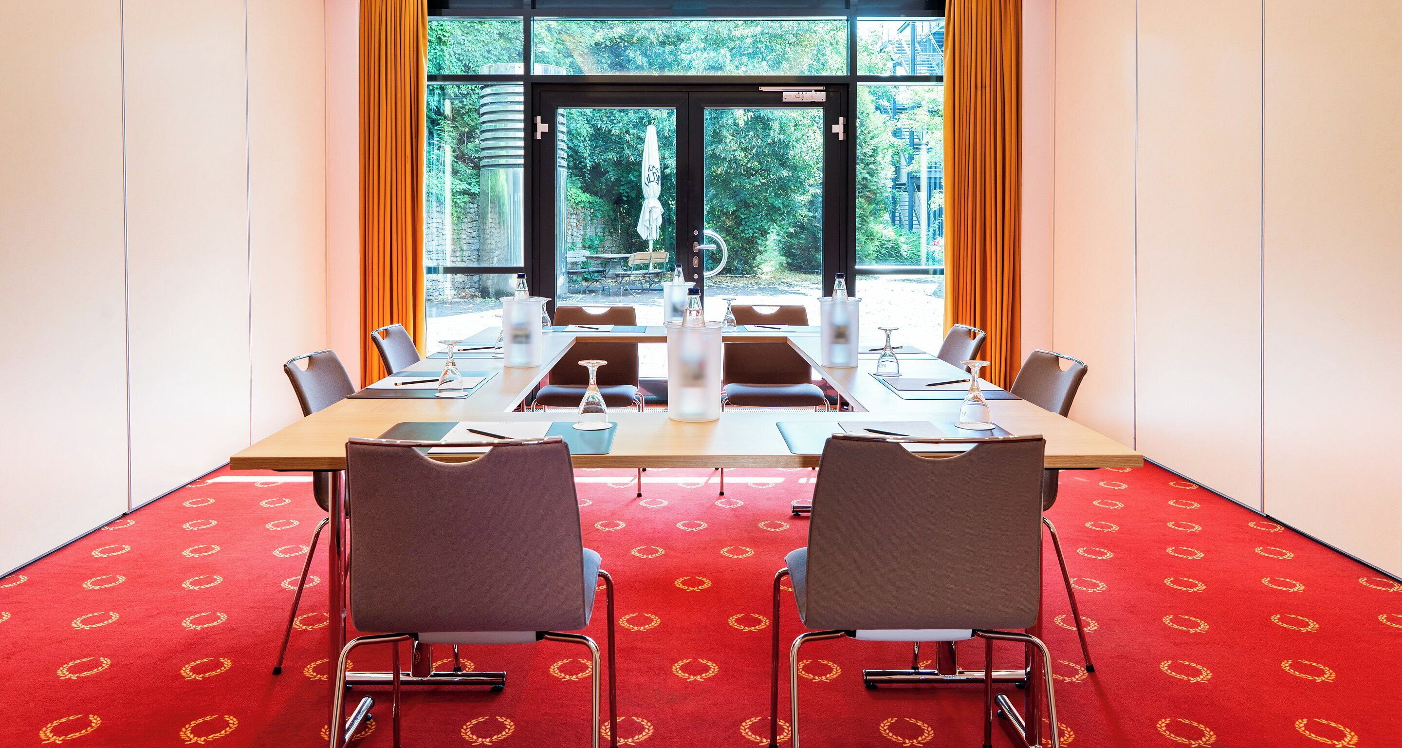 A conference room with a large table, chairs, and a red carpet.