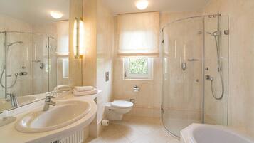 A modern bathroom with a large sink, toilet, and glass-enclosed shower.