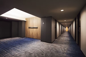 Un pasillo largo y estrecho con suelo alfombrado, pared de paneles de madera y un letrero con el número 4.