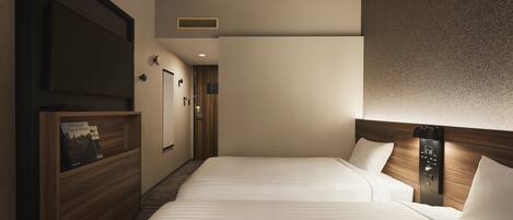 A hotel room with two beds, a wooden headboard, a wall-mounted control panel, and a bookshelf with books.