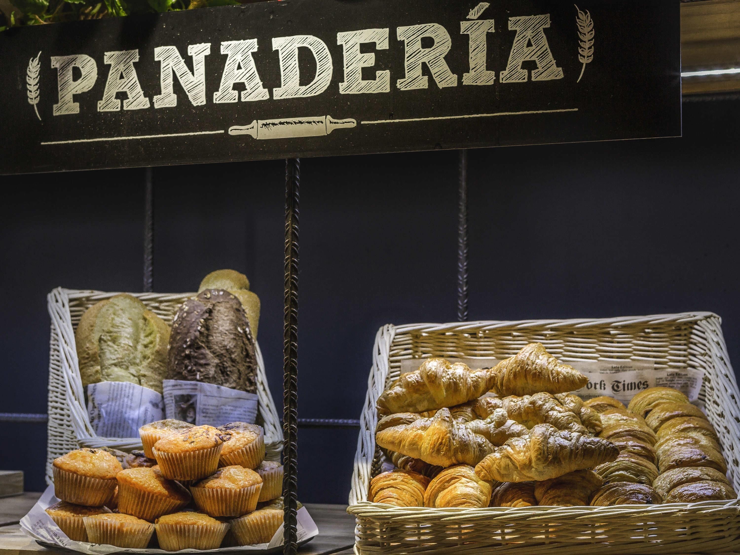 Une vitrine de boulangerie avec une pancarte indiquant « BOULANGERIE » et des paniers remplis de produits de boulangerie.