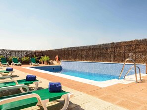 Una piscina al aire libre, sillones reclinables de piscina