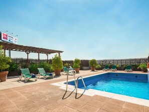 Een buitenzwembad, ligstoelen bij het zwembad