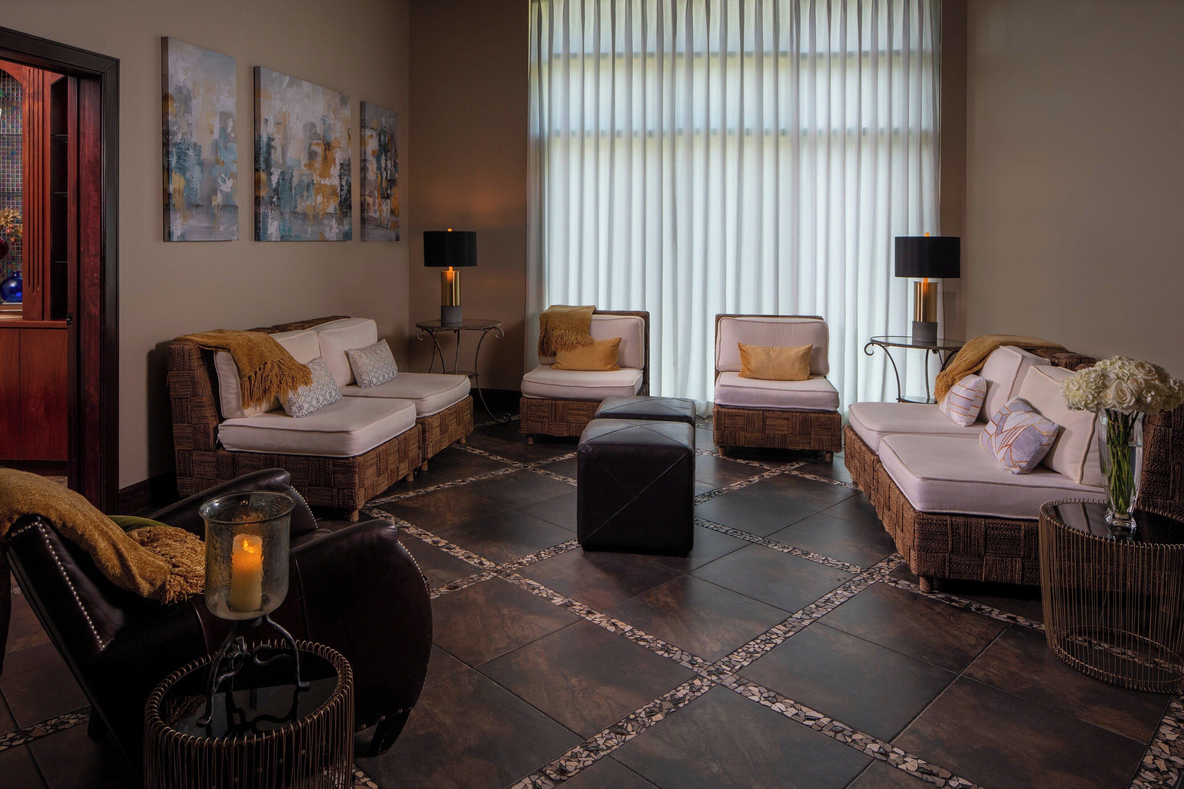 A cozy living room with wicker furniture, a large window with sheer curtains, and a decorative vase on a side table.