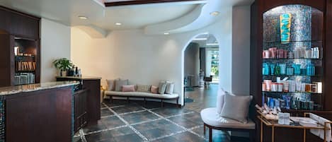 A spacious lobby with a seating area, a reception desk, and a display of toiletries.