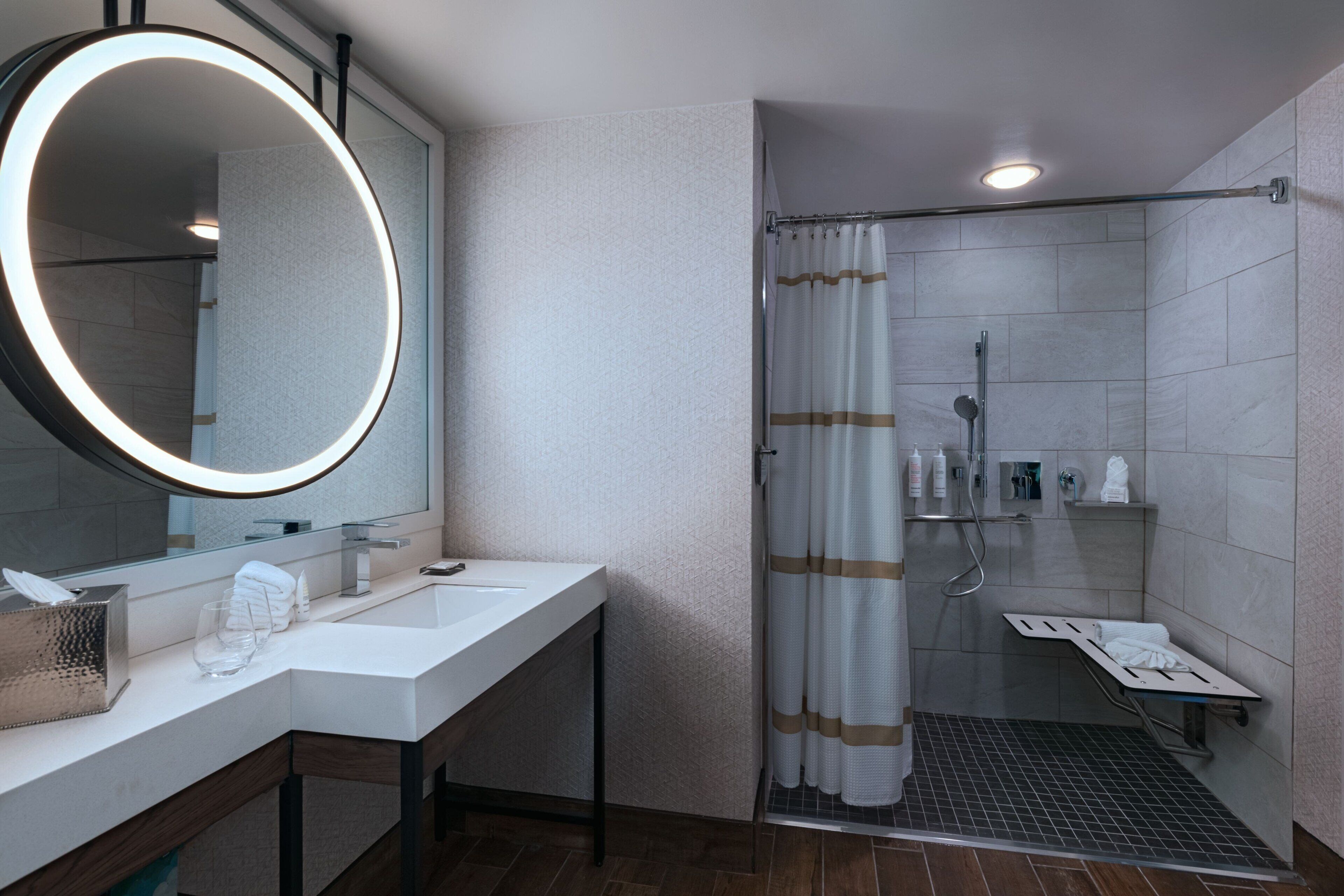 A modern bathroom with a large mirror, a sink, and a shower area.