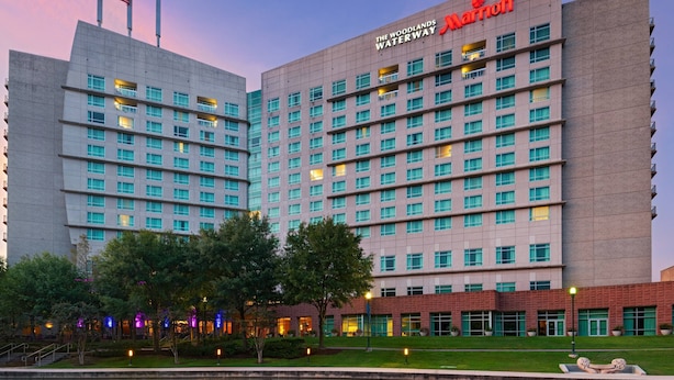 Un grand hôtel à plusieurs étages, avec un logo Marriott bien visible et un drapeau au sommet.