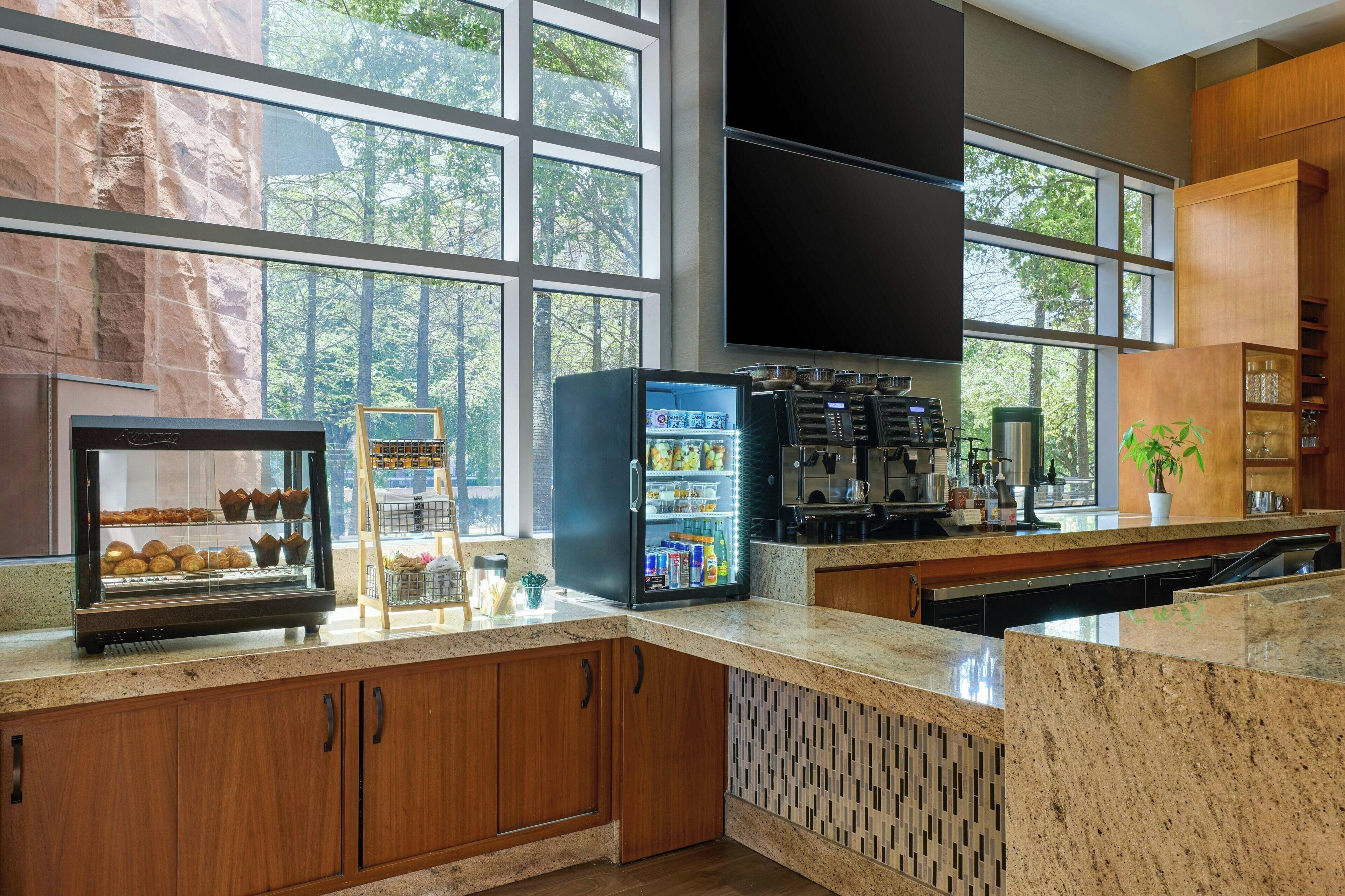 A modern kitchen with a stone wall, a coffee machine, a refrigerator, and a large window.