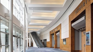 Un hall d’entrée spacieux, doté d’un haut plafond, de grandes fenêtres et d’un escalier mécanique central.