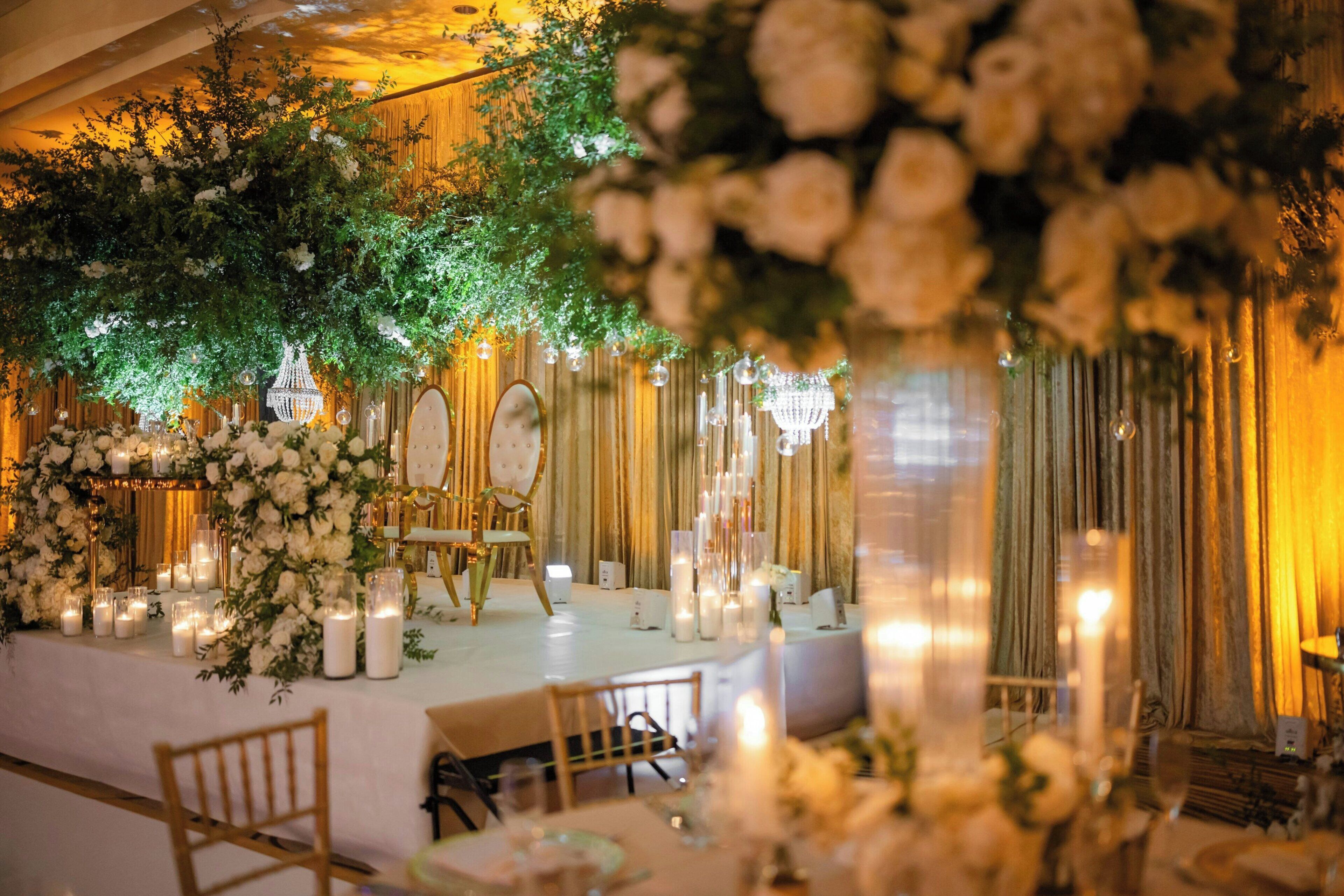 Un espacio interior para eventos con escenario, arreglos florales y asientos.