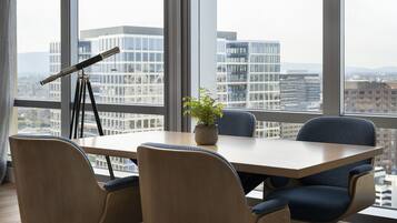 A conference room with a large table, four chairs, a telescope, and a potted plant.